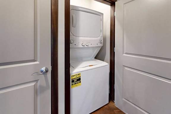 A stacked full-sized washer and dryer in a laundry closet.