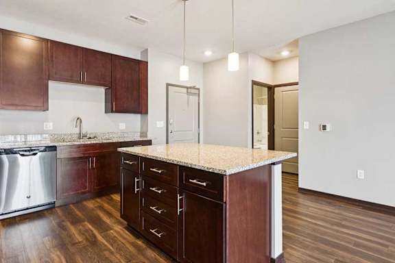 A kitchen with dark wood cabinets, granite countertops, and stainless steel appliances.