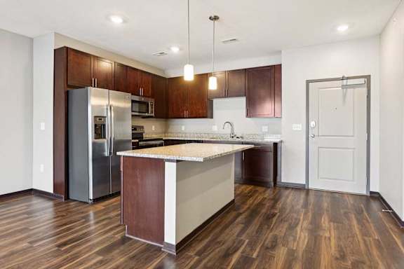 A kitchen with dark wood cabinets, granite countertops, and stainless steel appliances.