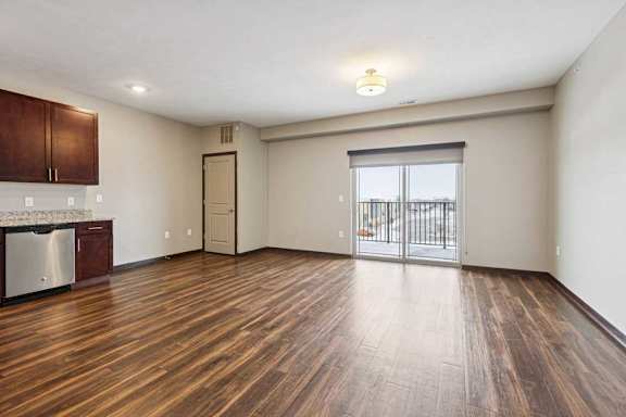 A living room with hardwood-style flooring and a sliding glass door to a balcony.