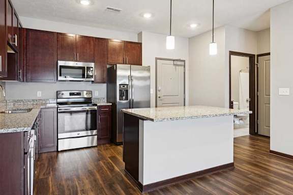 A kitchen with dark wood cabinets, granite countertops, and stainless steel appliances.
