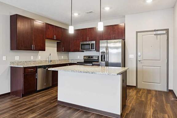 A kitchen with dark wood cabinets, granite countertops, and stainless steel appliances.