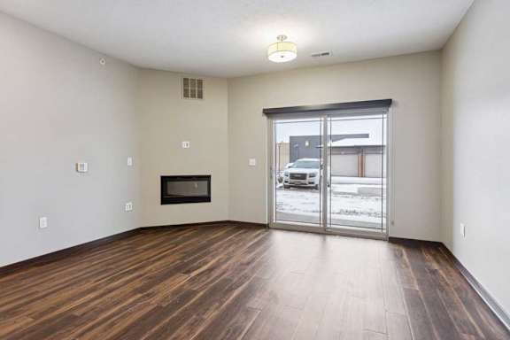 A living room with hardwood-style flooring, an electric fireplace, and a sliding glass door to a patio.
