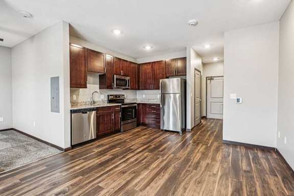 A kitchen with dark wood cabinets, granite countertops, and stainless steel appliances.