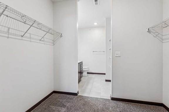 An oversized walk-in closet with several built-in wire shelves connected to an ensuite bathroom.