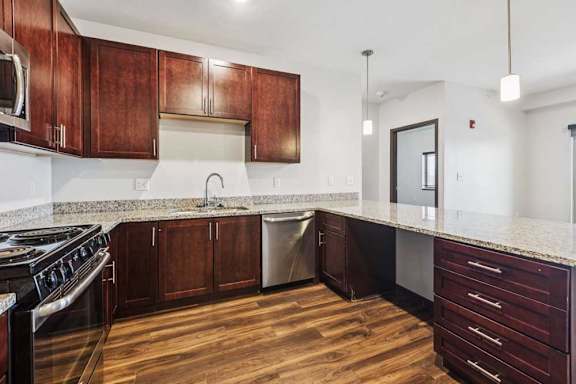 A kitchen with dark wood cabinets, granite countertops, and stainless steel appliances.