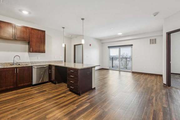 A large kitchen peninsula in front of a spacious living room and dining area.