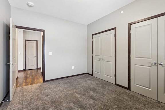 A carpeted bedroom with two double-door closets.