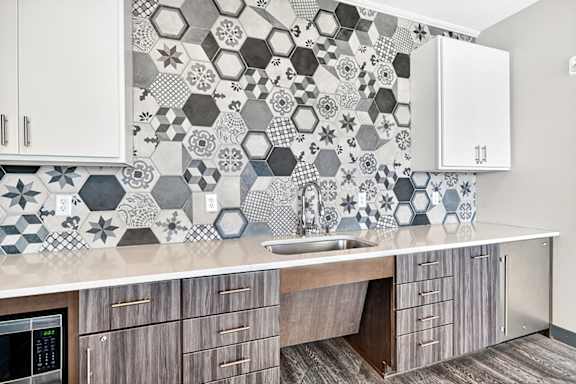 A kitchen with a tile backsplash and wooden cabinets.