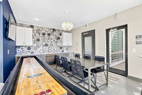 A room with a shuffleboard table in the middle.