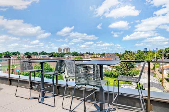 Two chairs are placed on a balcony overlooking a cityscape.