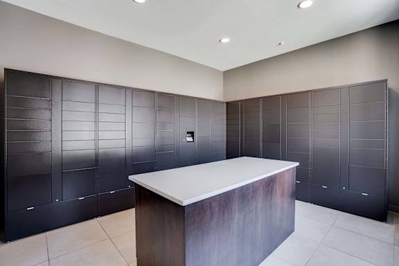 a room with wall to wall electronic package lockers with an island in the center