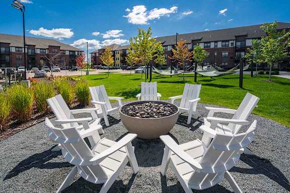 white Adirondack chairs surround a bowl-style fire pit