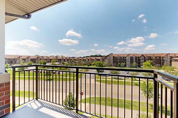 A balcony with a metal railing, overlooking the neighborhood.