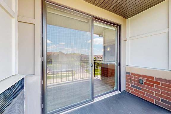 A balcony with a sliding glass door and a screen door.