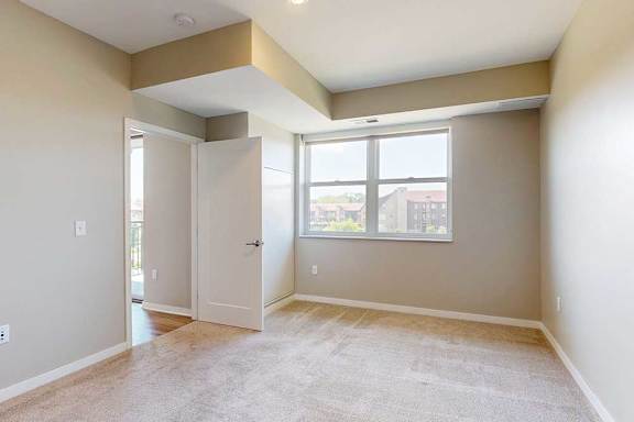 A carpeted bedroom with a large window.