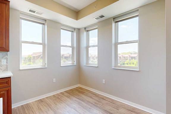 A dining room with hardwood-style flooring and several large windows for plenty of natural light.