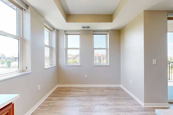 A dining room with hardwood-style flooring and several large windows for plenty of natural light.
