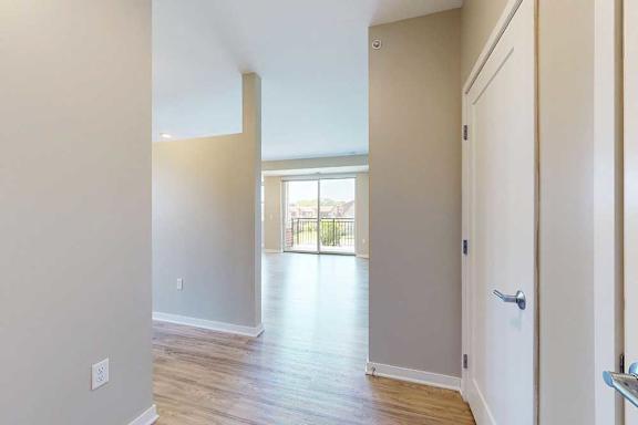 An enrty way open to a living room and a hallway connecting to a bedroom.
