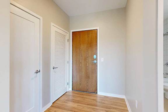 A front entryway with a wooden front door and a closed laundry room door.