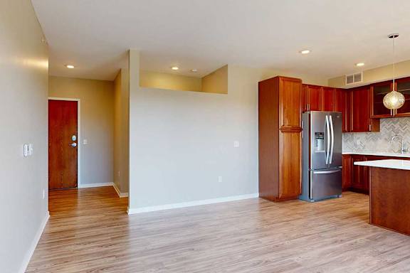 A living room with hardwood-style flooring, and a view of the front entryway.
