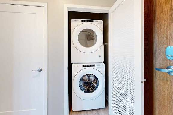 A laundry closet in the front entryway with a stacked, front-loading washer and dryer.