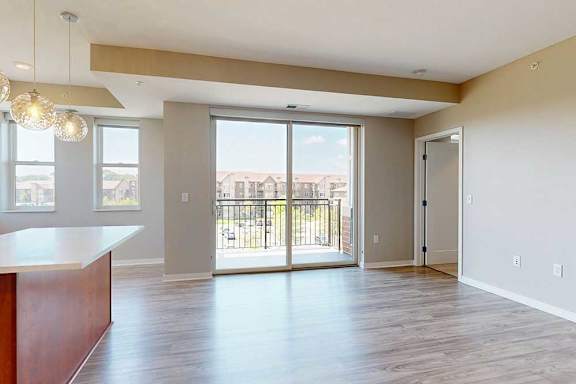 A living room with hardwood-style flooring and a sliding glass door to the balcony.