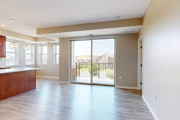 A living room with hardwood-style flooring and a sliding glass door to the balcony.