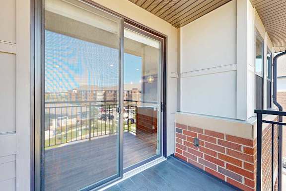 A balcony with a sliding glass door to the living room and a screen door.