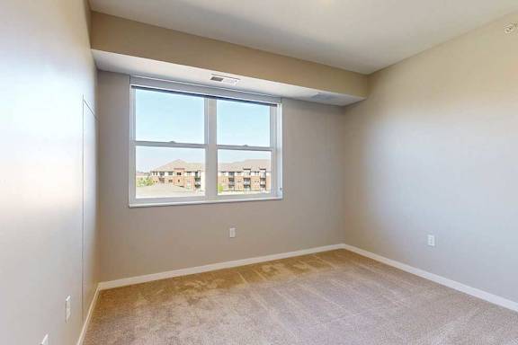 A carpeted bedroom with a large window.