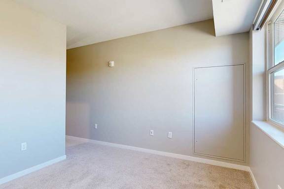 A carpeted bedroom with a large window.