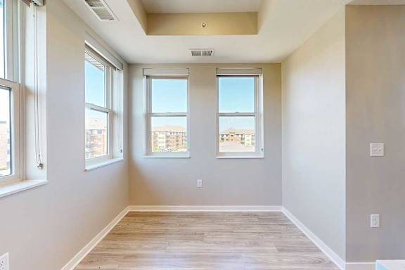 A dining area with several large windows and hardwood-style flooring.