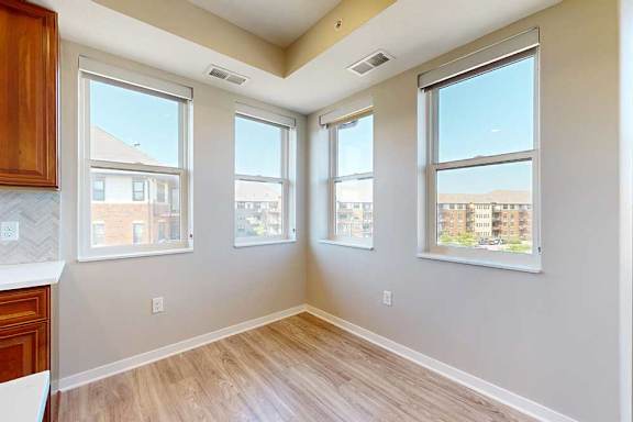 A dining room with hardwood-style flooring, and several large windows for natural light.
