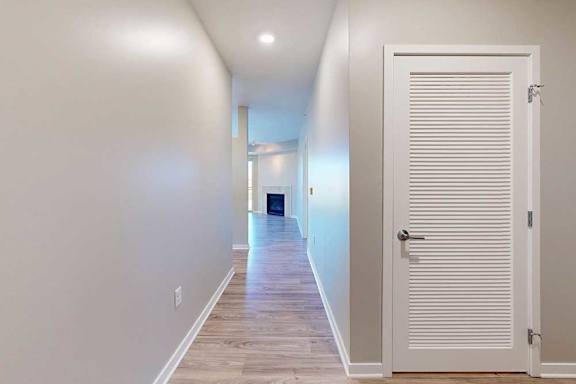 A long hallway with a white door to the laundry room.