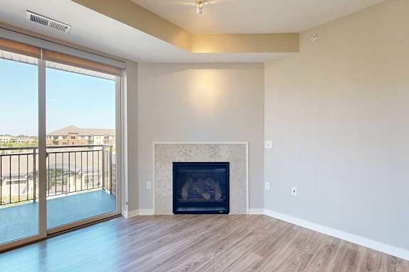 A spacious living room with hardwood-style flooring, a built-in fireplace, and a sliding glass door to a balcony.