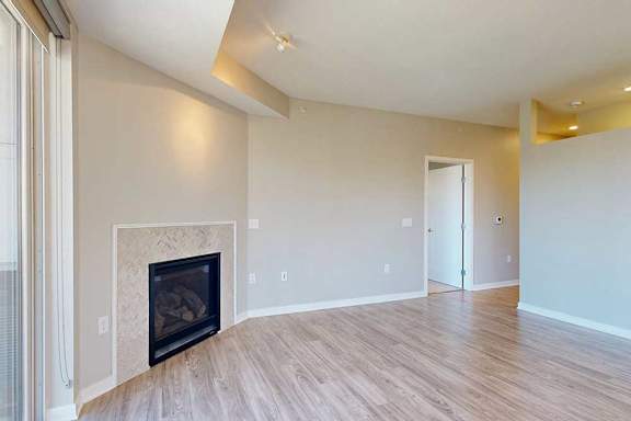 A spacious living room with hardwood-style flooring and a built-in fireplace.