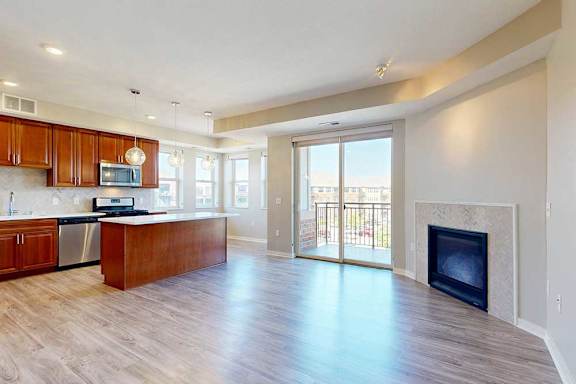 A spacious living room with hardwood-style flooring, a built-in fireplace, and a sliding glass door to a balcony.