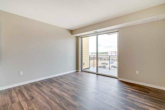 A living room with hardwood-style flooring and a sliding glass door to a balcony.