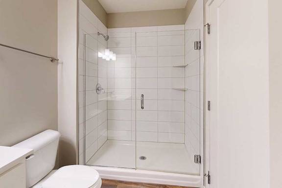 A modern bathroom with a tiled walk-in shower and a glass door.