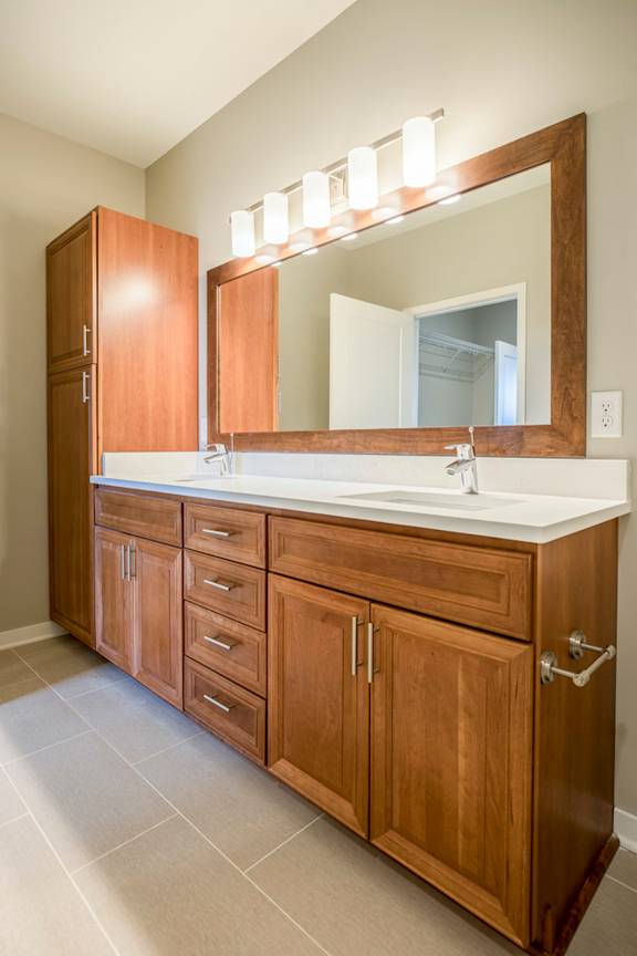 A bathroom with a sink, mirror, and tons of cabinets.