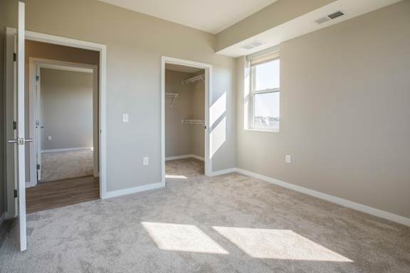 A room with a carpeted floor and a window letting in sunlight.