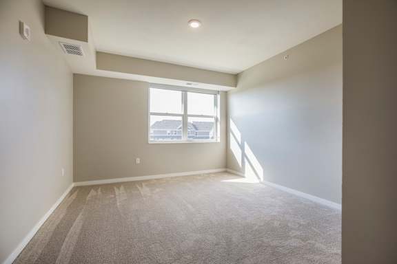 A bedroom with a window and carpeted floor.