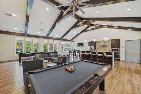 A pool table is in the middle of a room with a ceiling fan.