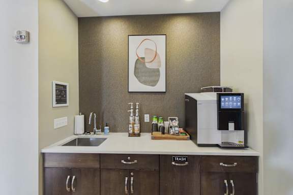 A kitchen with a sink, a coffee maker, and a fridge.