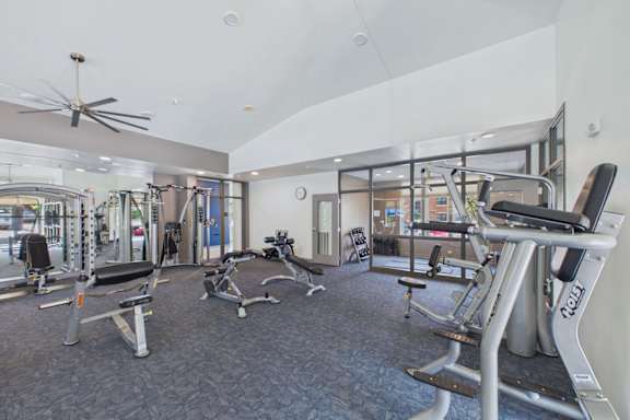 A gym with a variety of equipment including treadmills, weights, and a fan.