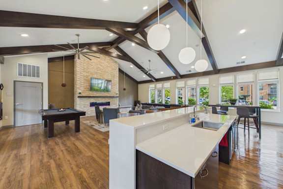 A modern kitchen with a pool table in the middle.