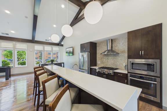 A modern kitchen with a long white island and wooden chairs.