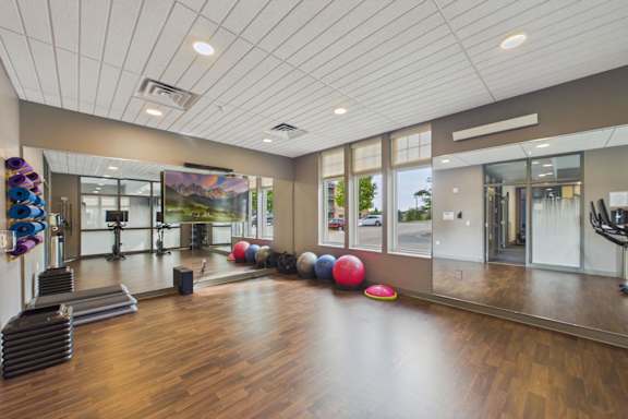 A gym with a variety of equipment including a treadmill, weights, and exercise balls.
