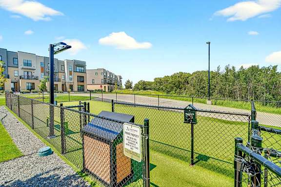 Fenced dog park with waste station and open turf area, located within a pet-friendly apartment community.