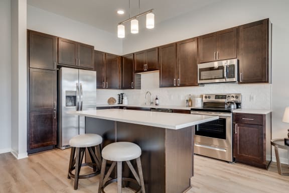 Luxury kitchen with white cabinets and an island at Aspire at CityPlace in Woodbury MN 55125